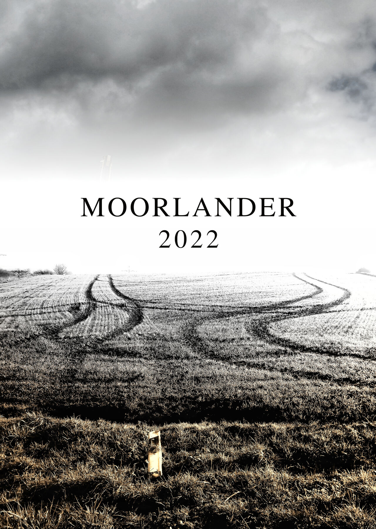 Kalenderdeckblatt mit der Aufschrift Moorlander 2022 zwischen düsterem Himmel und einer Ackerszene zweier sich zunächst annähernder, dann parallel verlaufender Traktorspuren im Stoppelacker.